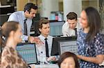 Businessmen working at computer in open plan office