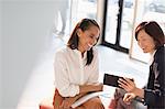 Smiling businesswomen using digital tablet in office lobby