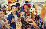 Women friends toasting wine and beer glasses at bar