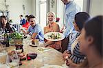 Waiter serving salad to woman dining with friends at restaurant table