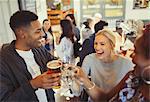 Laughing friends toasting beer and wine glasses at bar