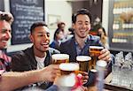 Men friends toasting beer glasses at bar