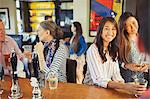 Women smiling at bartender and drinking at bar