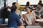 Laughing women friends talking and drinking wine in bar