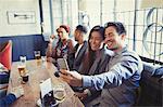 Smiling couple taking selfie with camera phone at table in bar