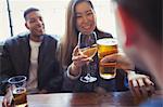 Friends celebrating, toasting beer and wine at table in bar