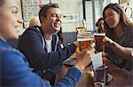 Friends celebrating, toasting beer and wine glasses at table in bar