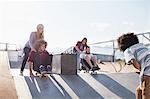 Friends pushing each other on skateboards at sunny skate park