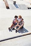 Overhead view male friends taking selfie with camera phone at sunny skate park