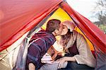 Young couple camping, kissing inside tent