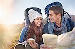 Young couple with backpacks hiking checking map