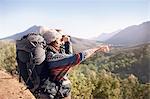 Young couple hiking, looking at sunny view with binoculars