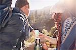 Young couple hiking, taking a coffee break and using smart phone