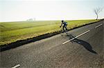 A cyclist riding along a country road on a clear sunny winter day.