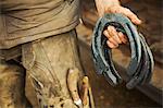 A farrier holding a handful of metal horseshoes.