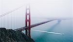 The Golden Gate bridge in the mist, with a boat sailing underneath.