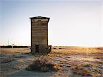 A wooden tower standing in a flat landscape of scrubland.