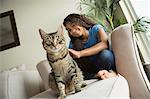 A girl sitting on a sofa with a pet cat.