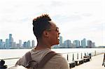 Young man strolling along East river waterfront, New York, USA