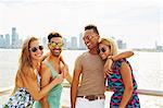 Portrait of four adult friends on waterfront with skyline, New York, USA