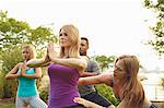 Yoga teacher adjusting woman's yoga position in park