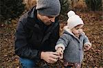 Father holding hand of baby girl in forest