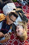 Overhead view of couple on picnic blanket sharing earphone music