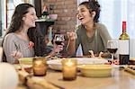 Two young women friends eating meal at kitchen table