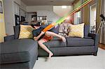 Young boy on sofa, wearing virtual reality headset, firing laser guns, digital composite