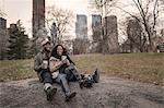 Couple sitting on rock in park with takeaway coffee