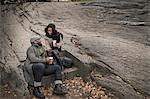 Couple sitting on step in park with takeaway coffee