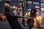 Couple holding hands around illuminated tree at night, New York, USA