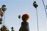 Teenage boy with red afro hair, outdoors, rear view