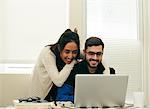 Happy couple using laptop at home