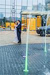 Couple standing together, dancing, outside building, wearing evening clothes