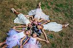 Group of young girls dressed as fairies, lying in circle, heads together