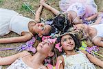 Group of young girls dressed as fairies, lying in circle, heads together