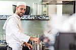 Portrait of chef stirring pan on stove