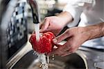 Chef washing pepper red pepper under tap, close-up