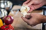 Chef peeling fresh garlic, close-up