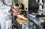 Chef chopping green pepper on chopping board