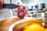 Chef preparing to slice red onion, close-up