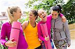 Happy female friends with yoga mats