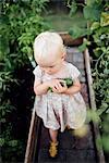 Girl in greenhouse holding cucumber