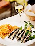 Sardines with chips on plate