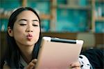 Young woman blowing kiss while video conferencing on digital tablet
