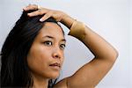 Woman looking away in thought with hand on head, portrait