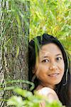 Woman leaning against tree trunk, portrait