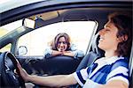 Woman looking into car window while man sitting in driver seat