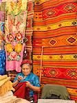Woman sewing in market with background of handmade rugs, Oaxaca, Mexico, North America